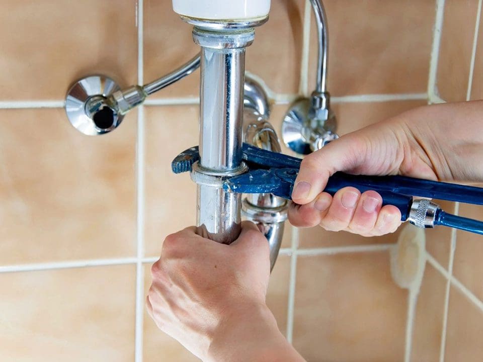 A person is fixing the faucet of a bathroom.
