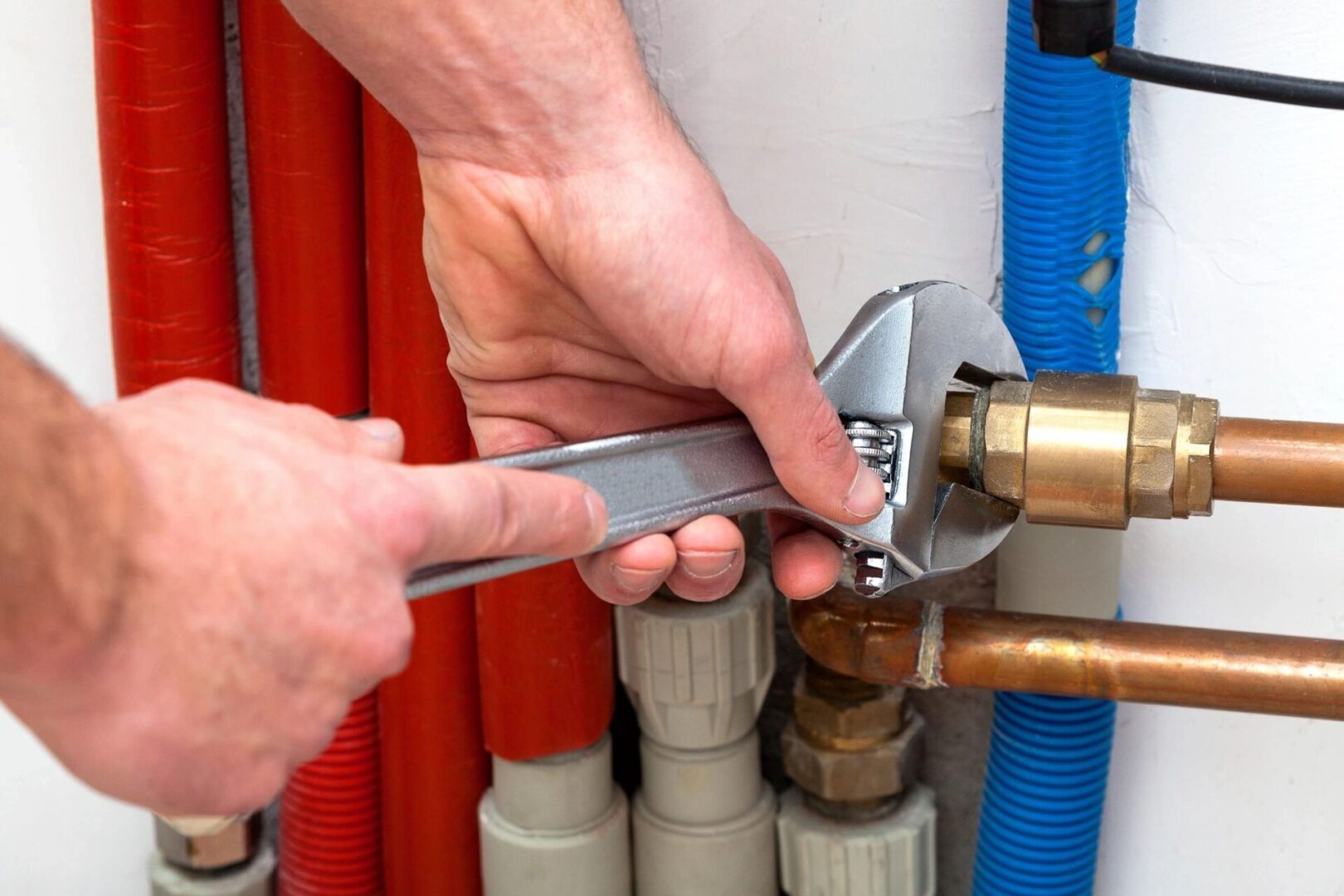A person is holding a wrench over the water heater.